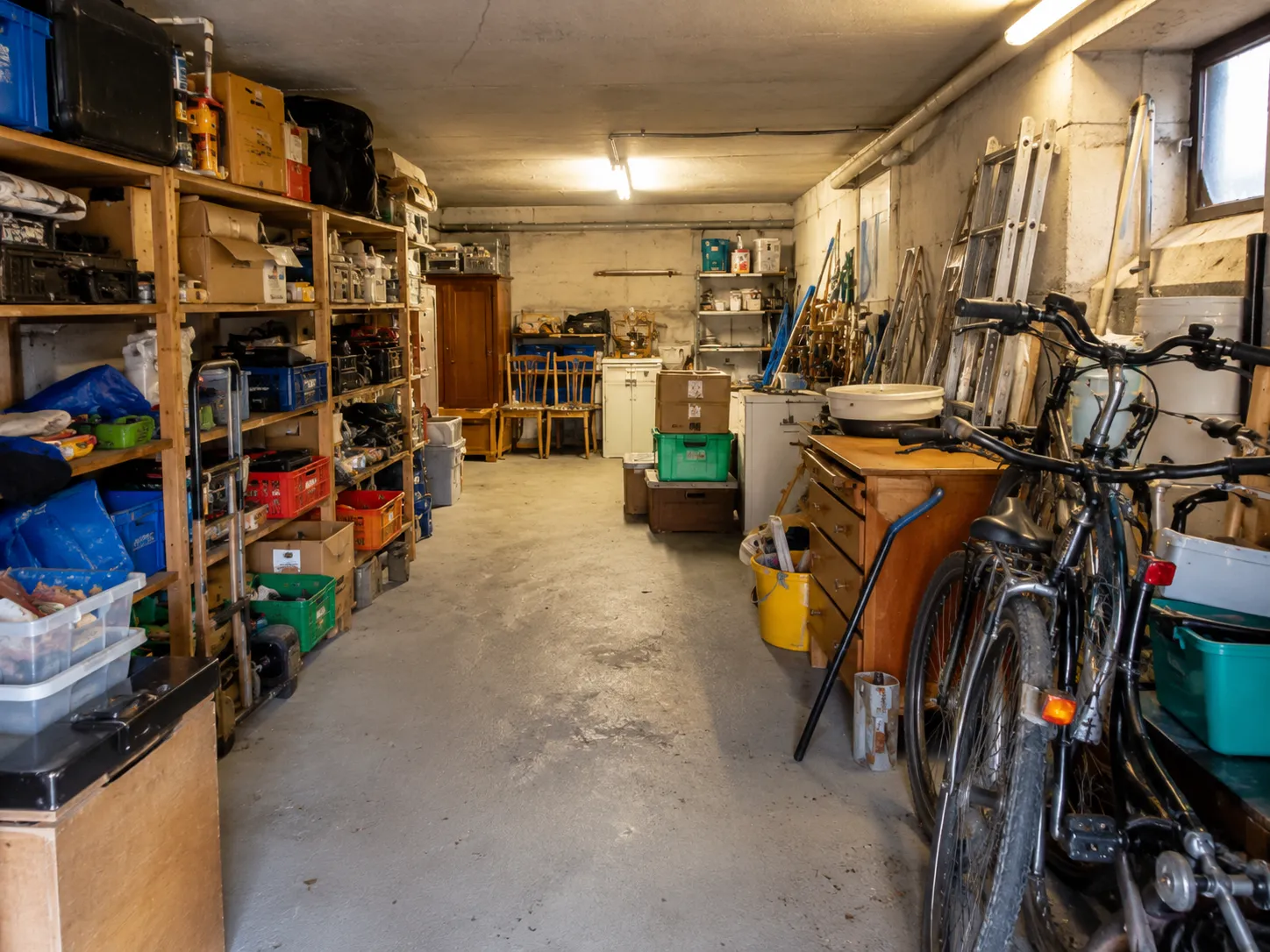 Garagen- und Kellerentrümpelung – vollgestellte Garage mit Regalen und Fahrrädern