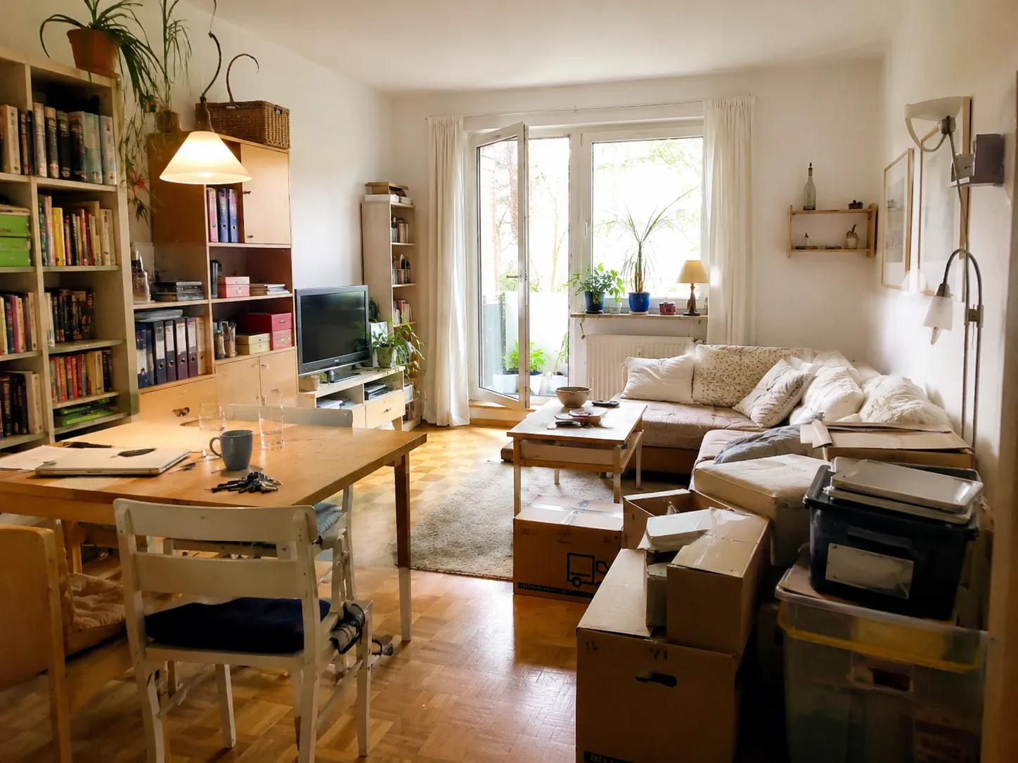 Wohnungsräumung in München – Wohnzimmer mit Umzugskartons und Bücherregal
